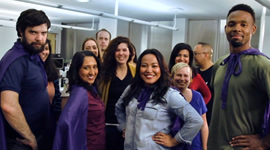 A group of smiling people, some wearing purple capes